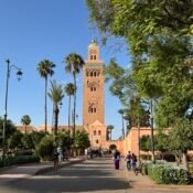 View of the iconic Koutoubia Mosque in Marrakech surrounded by lush gardens and palm trees, a must-see attraction for first-time visitors