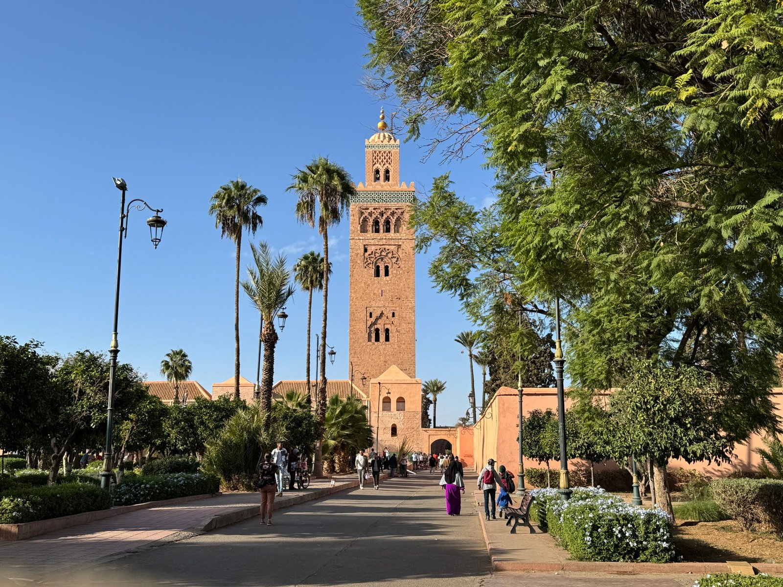 View of the iconic Koutoubia Mosque in Marrakech surrounded by lush gardens and palm trees, a must-see attraction for first-time visitors