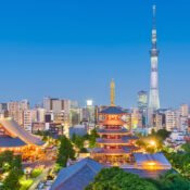 Tokyo skyline at dusk featuring the illuminated Senso-ji Temple and its five-story pagoda in Asakusa, with the towering Tokyo Skytree in the background, surrounded by a mix of modern and traditional architecture.