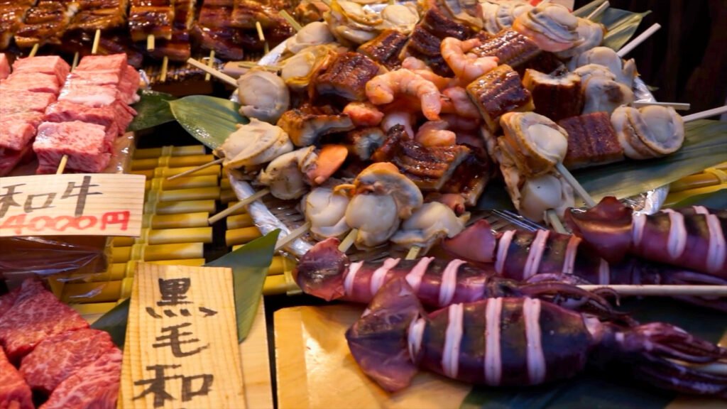 A vibrant seafood and meat display at Tsukiji Outer Market in Tokyo, Japan, featuring skewers of grilled eel, scallops, shrimp, squid, and premium Wagyu beef, showcasing the rich variety of fresh Japanese street food.